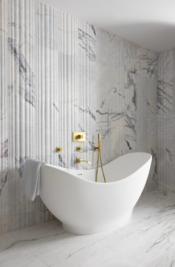 Freestanding tub area with textured marble tile and sculptural detail